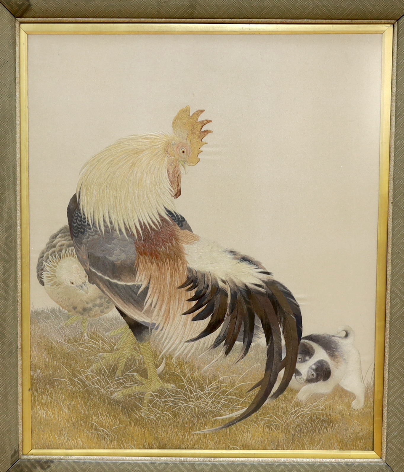 A large framed early 20th century Japanese silk polychrome embroidery of a cockerel, it’s chick and puppy by the chicken’s tail feathers, 63cm wide x 75cm high, not including mount or frame